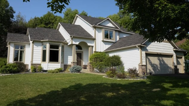 Two-story suburban house with lawn and trees.