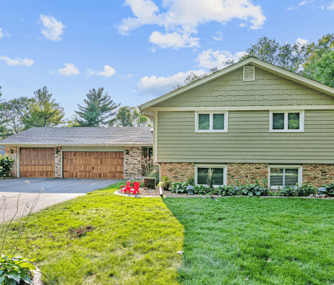 Suburban house with green lawn and red chairs