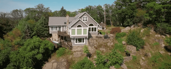 Aerial view of house surrounded by trees and rocks.