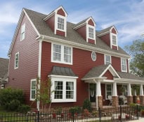 Large red house with white trim and fence.