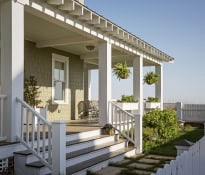 Charming porch with plants and white railings.