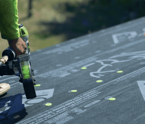 Worker installing roofing with nail gun