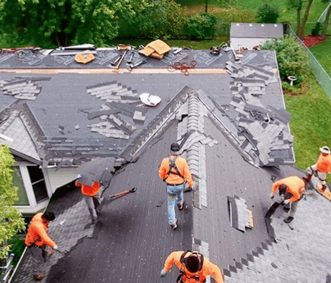 Workers installing shingles on roof, aerial view.