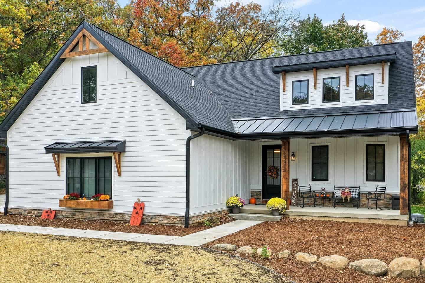 White farmhouse with fall decorations and porch seating.