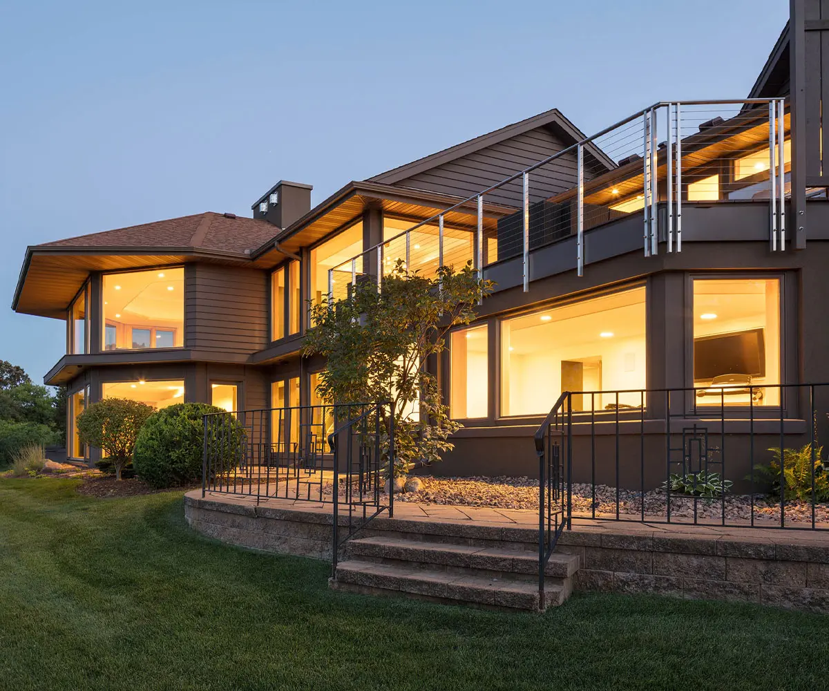 Modern house with large windows and garden at dusk.