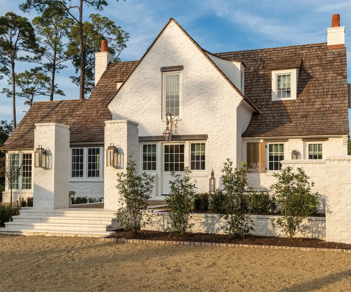 Charming white brick house with wooden roof shingles.