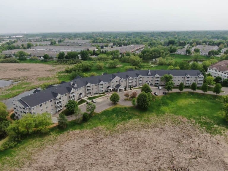 Aerial view of large country building and green fields.