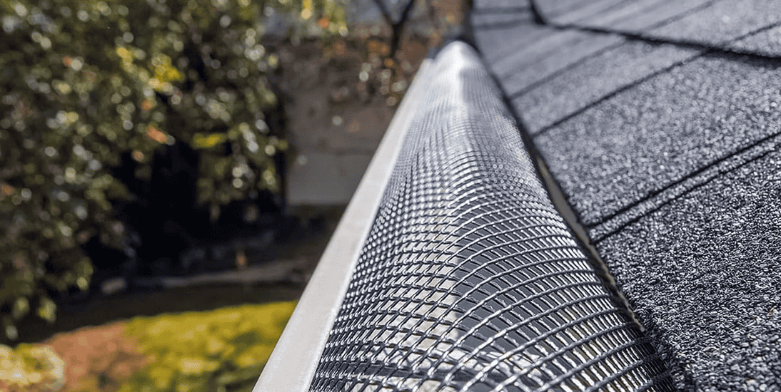 Gutter guard with mesh on rooftop edge.