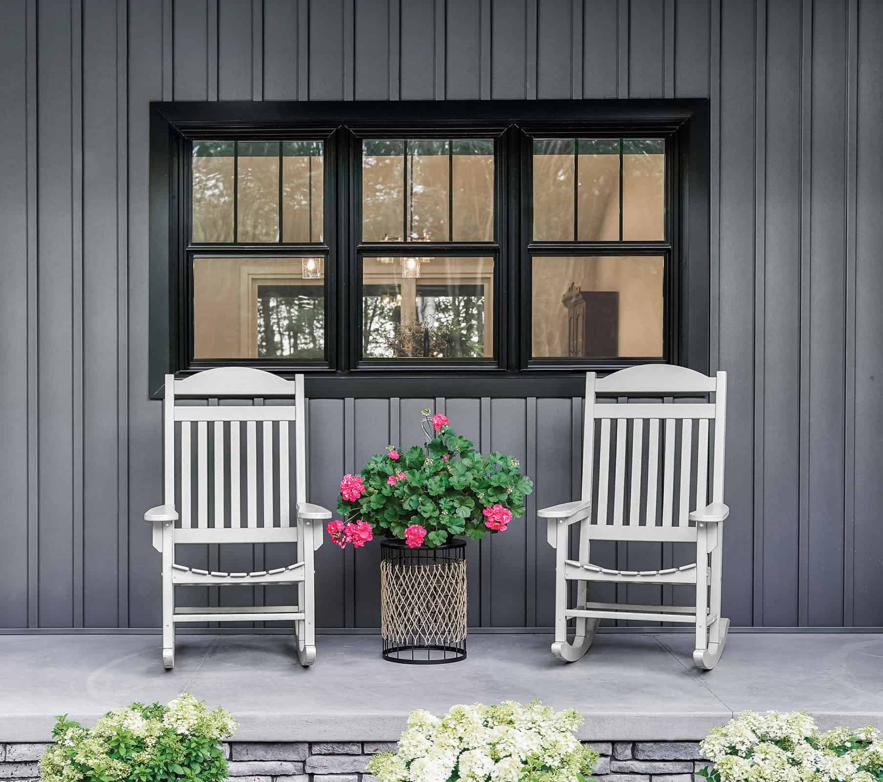 Grey porch with rocking chairs and pink flowers.