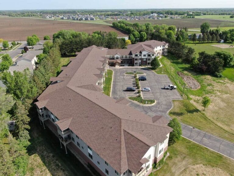 Aerial view of large building with parking lot and fields.