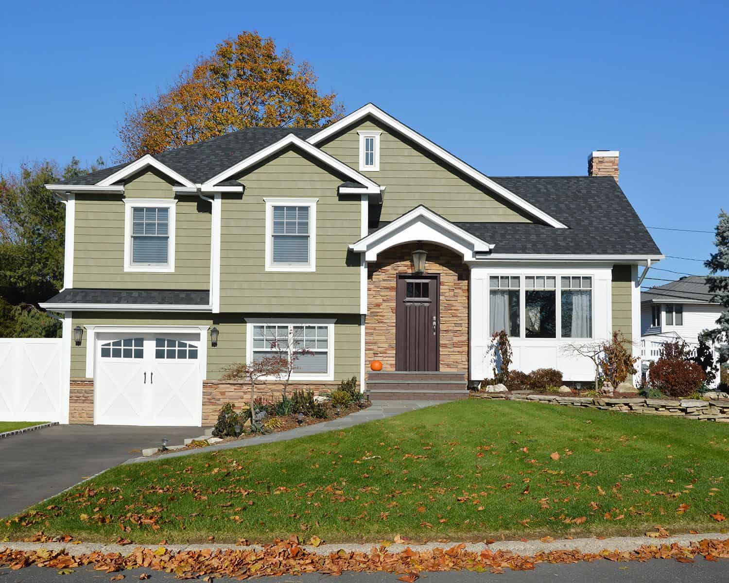Green suburban two-story house with garage and lawn