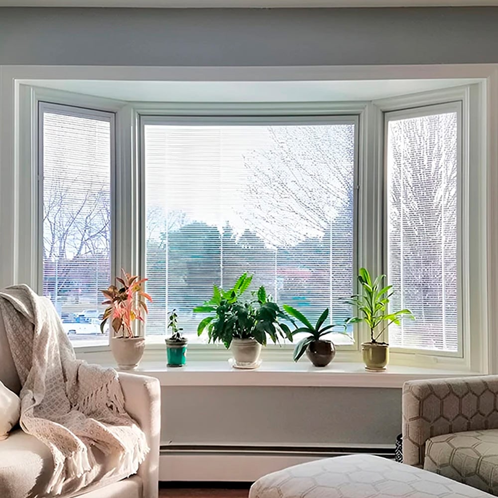 Bright bay window with potted plants and blinds