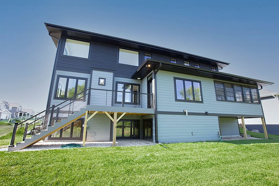 Modern elevated home with exterior stairs and large windows