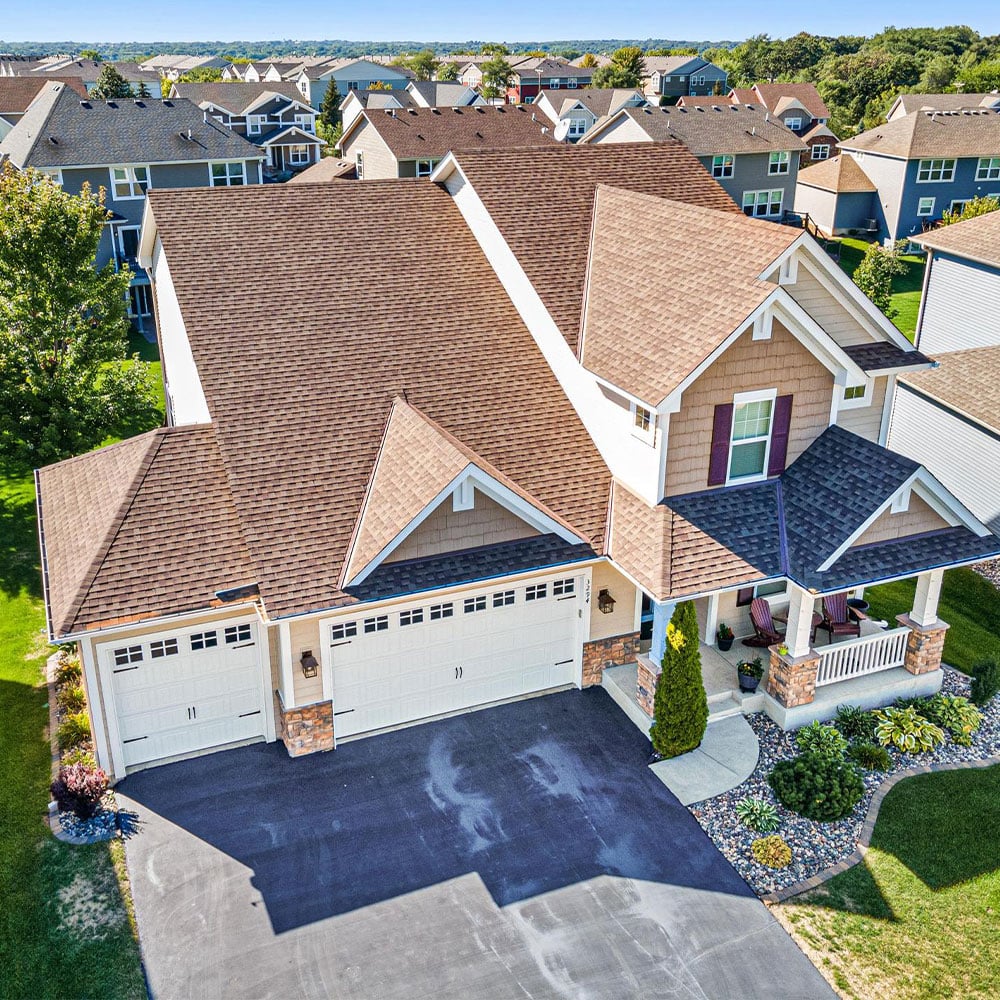 Aerial view of suburban home with shingle roof