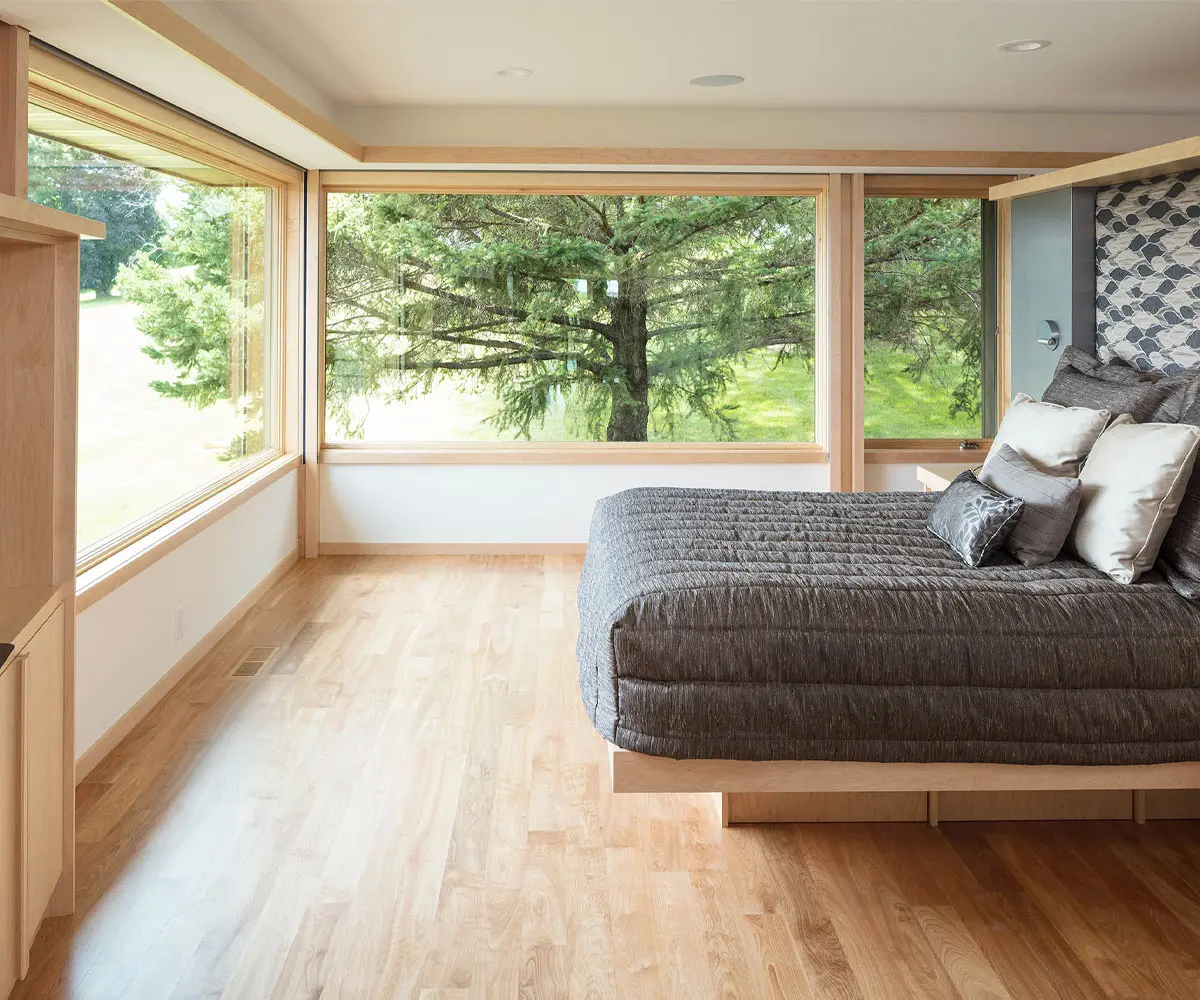 Modern bedroom with large windows overlooking lush trees