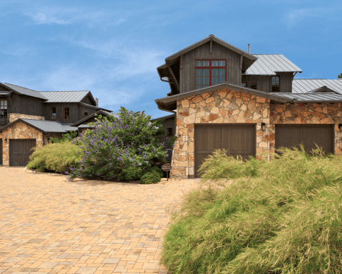 Rustic stone house with garages and landscaped driveway