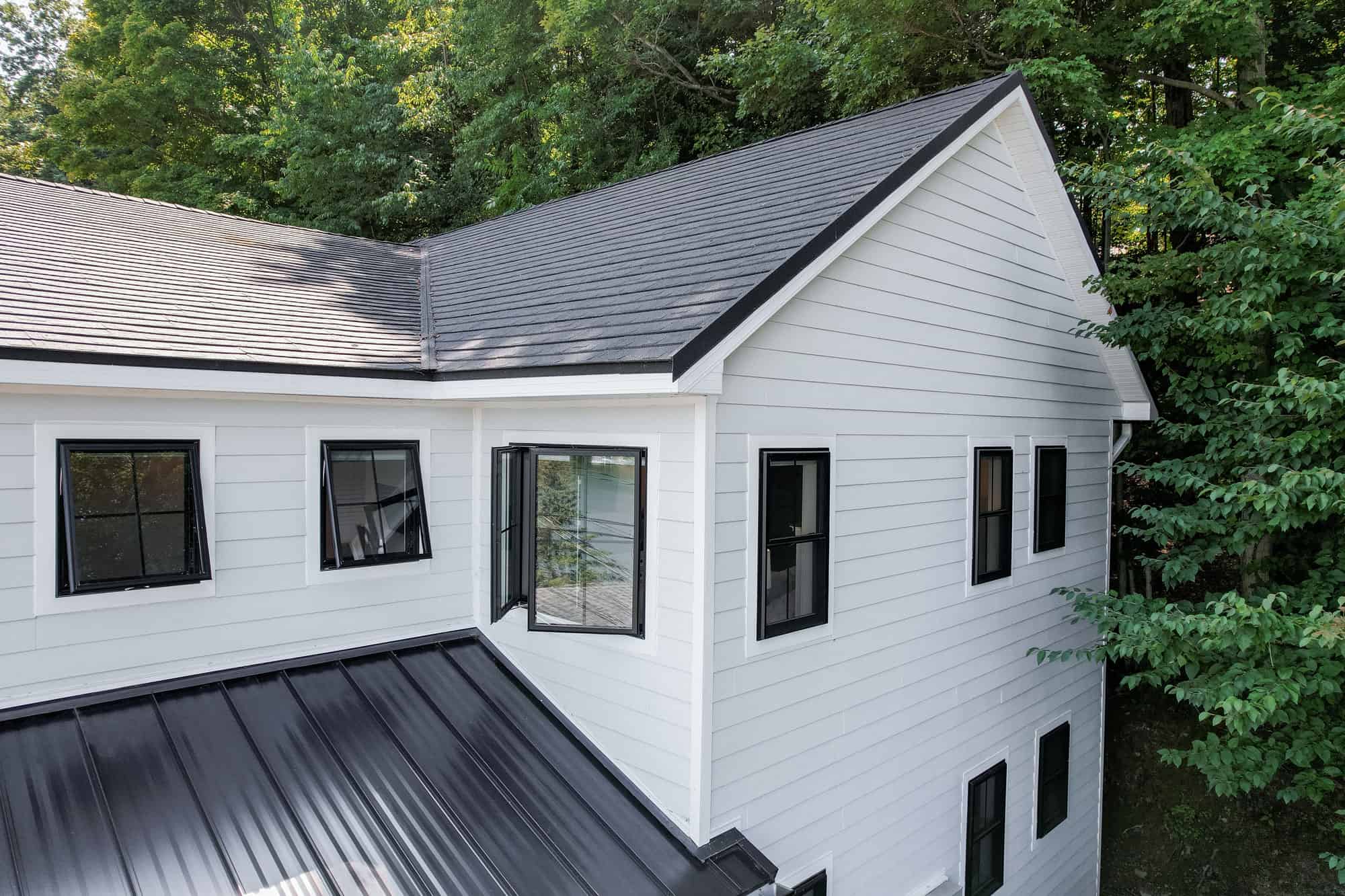 White house with black roof surrounded by trees