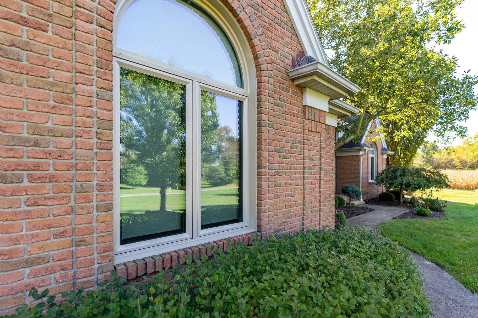 Arched window on landscaped brick house exterior